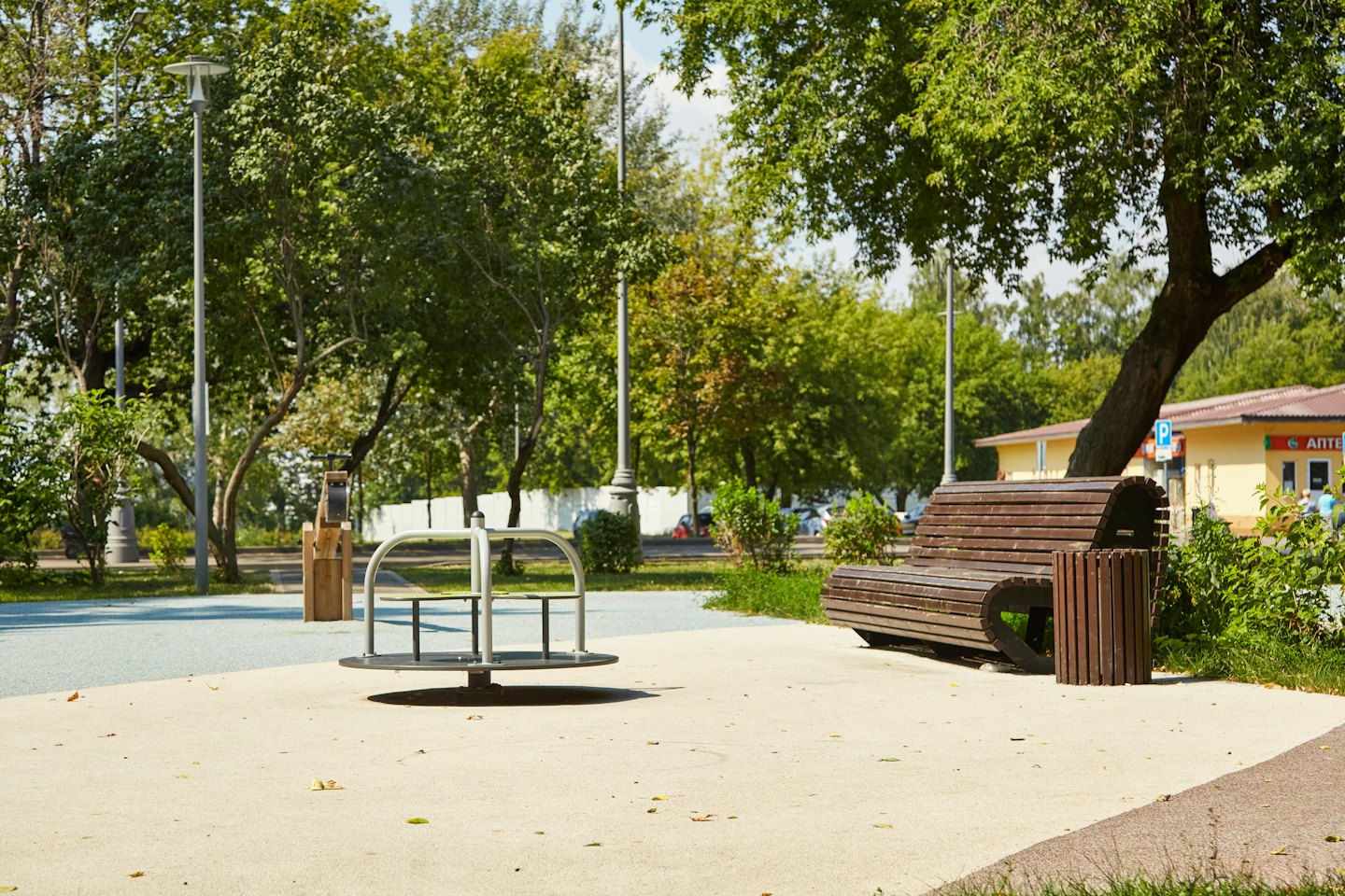 Leerer Spielplatz mit Karussell und Holzbank.