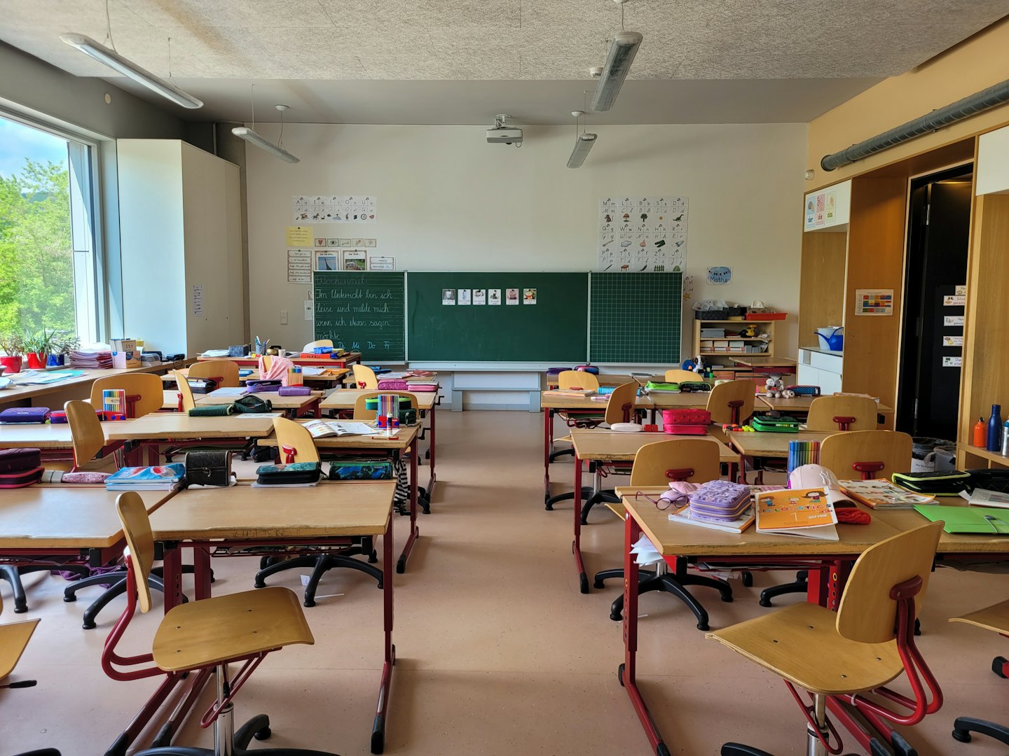 Leerer moderner Klassenraum mit Reihen von Schreibtischen und einer Tafel.